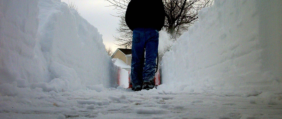 Man snow blowing a residential sidewalk moving the snow aside and clearing a path in Sioux Falls, SD.