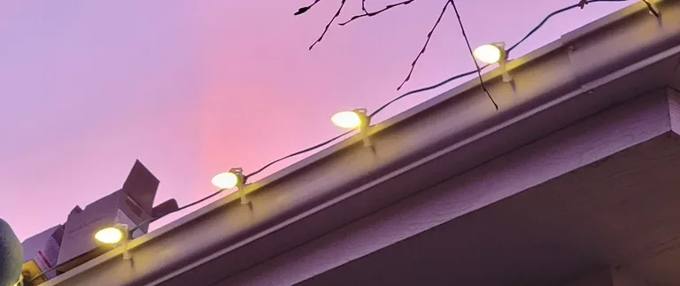 Close view of the larger roofline bulbs clipped along a gutter line at dusk