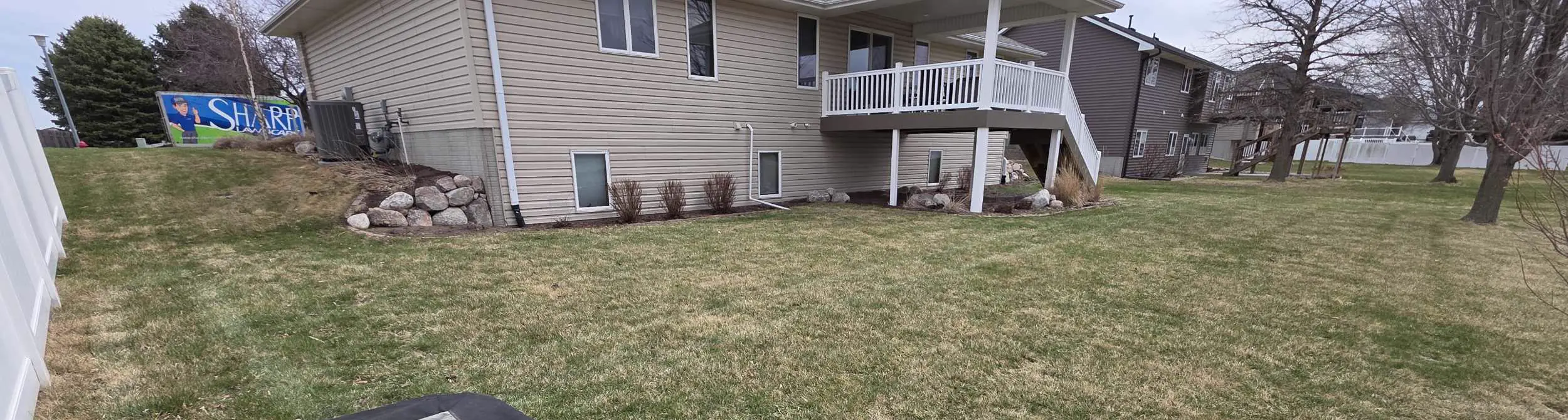 Lawn beginning to green up in spring with remaining brown patches near a Siouxland home