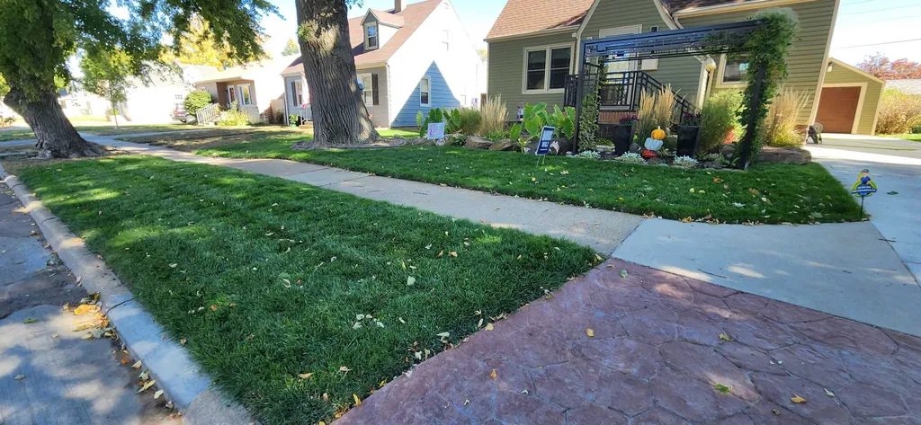 Well-maintained residential front yard with thick green grass from a premium lawn care program in Sioux City, IA