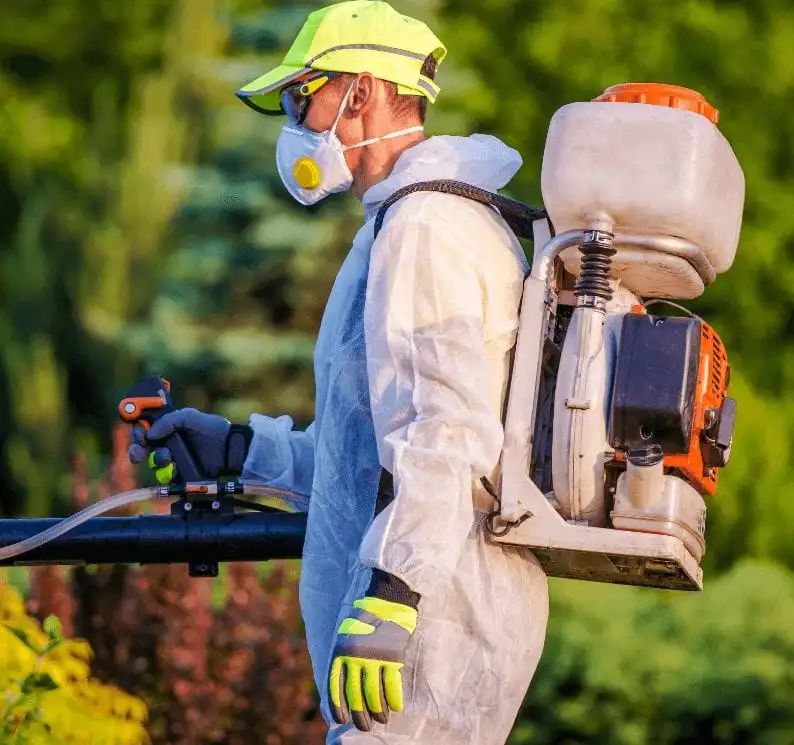 Lawn care worker with protective gear spraying herbicides in Sioux City, IA.
