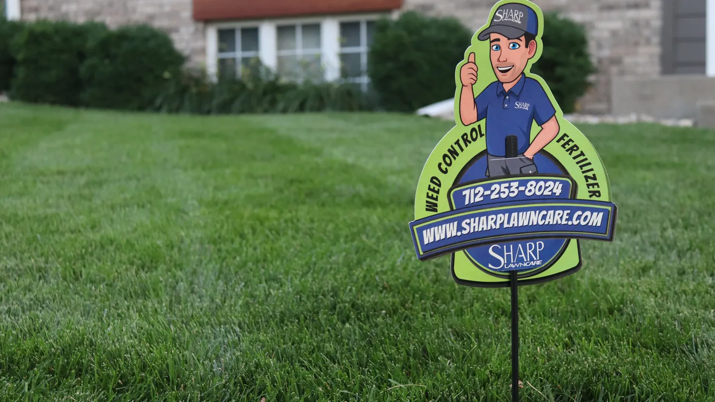 Sharp Lawn Care yard sign on a beautifully maintained green lawn