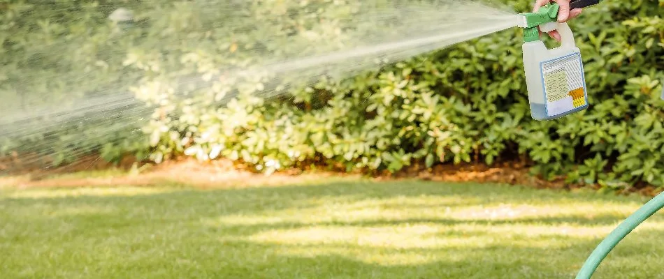 Person spraying a liquid aeration treatment to a lawn in Sioux Falls, SD.