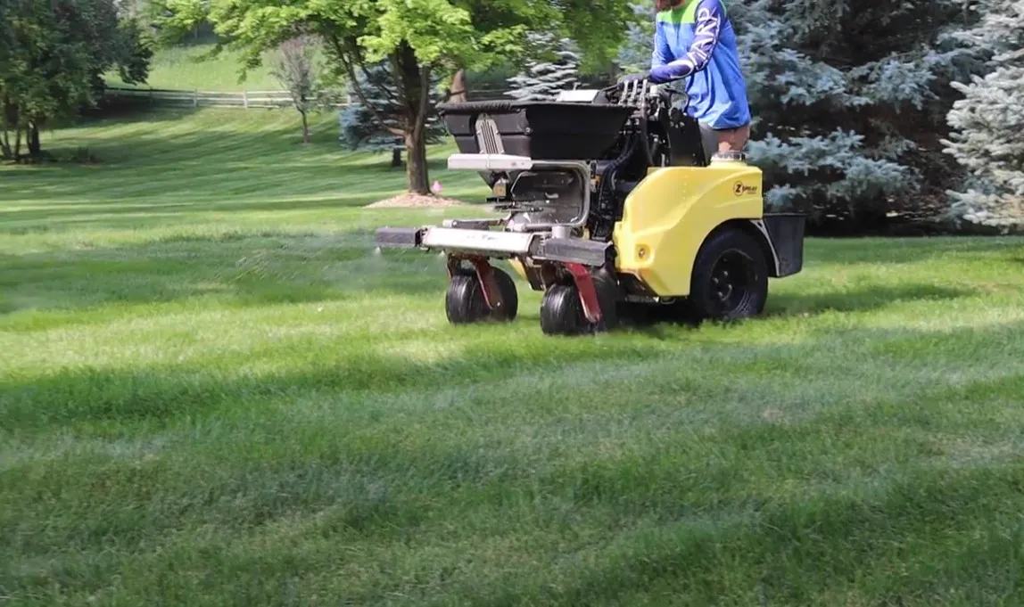 Professional lawn care technician applying fertilizer with a push spreader in Sioux Falls, SD