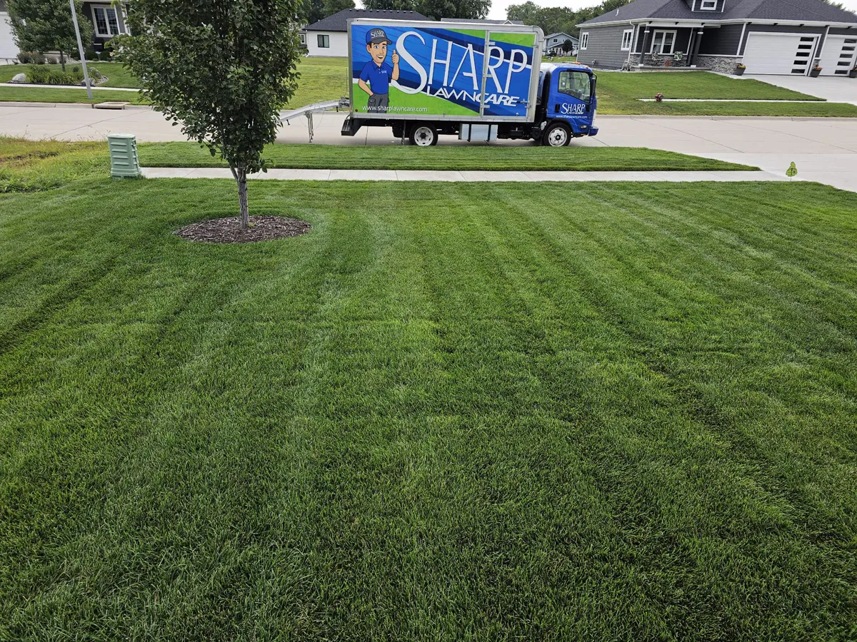 Sharp Lawn Care truck parked at a residential property with a well-maintained lawn in Sioux Falls, SD