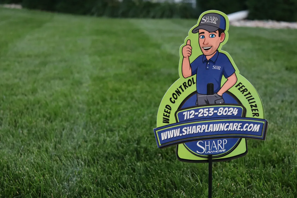 Sharp Lawn Care yard sign with mascot in a treated Sioux City IA lawn