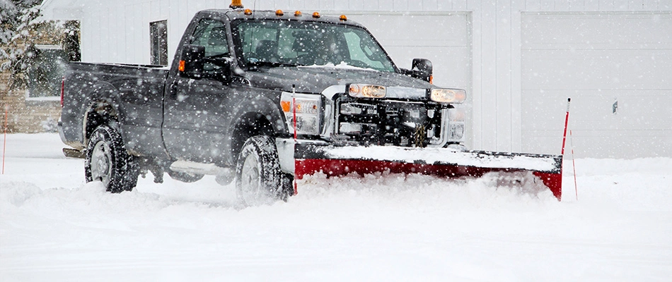 Truck with a snow shovel at the front is plowing a driveway for a customer near Sioux City, IA.