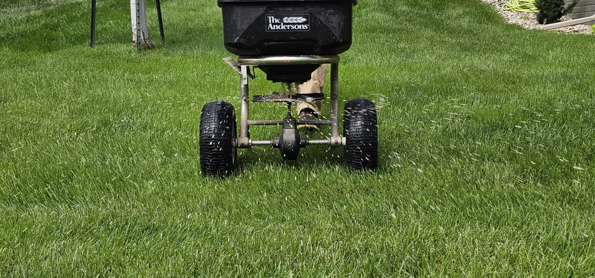 Fertilizer spreader hopper detail during lawn treatment in Harrisburg SD