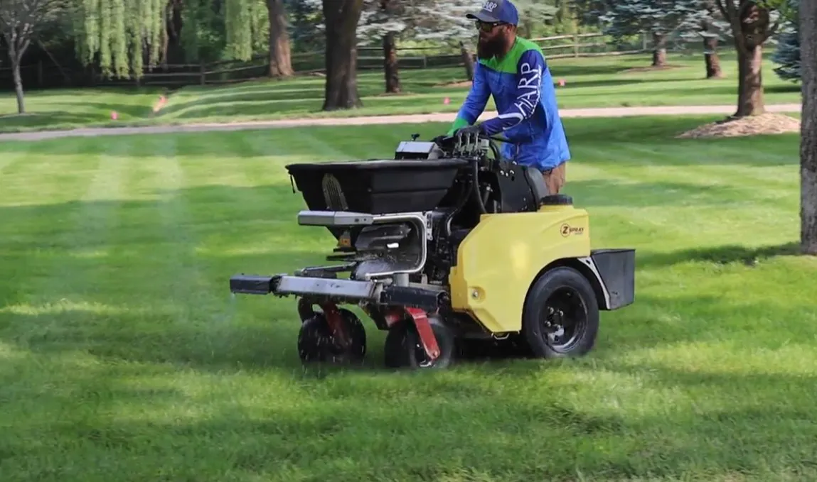 Tow-behind spreader applying lawn treatment on a residential property
