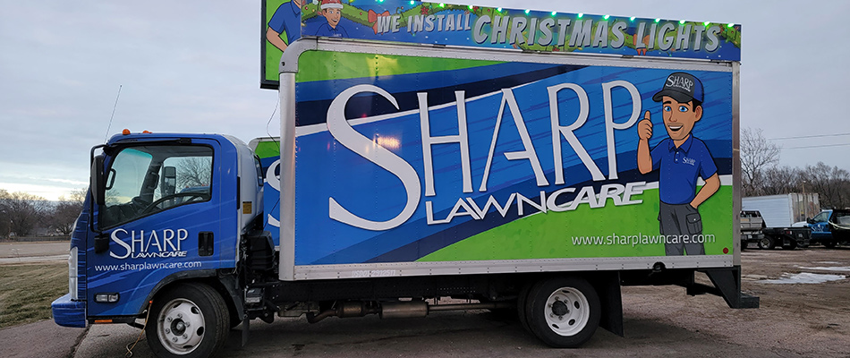 Sharp Lawn Care's work van with Christmas light ad in Sioux City, IA.