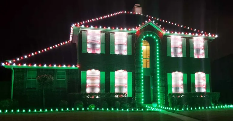 Green and red Christmas lights outlining a roofline and every front window of a home