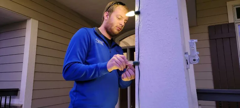 A Sharp Lawn Care installer working at a front entry during a Christmas light installation