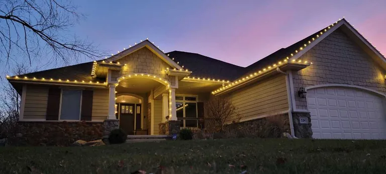 Warm white roofline lights and a lit entry portico on a ranch at blue hour