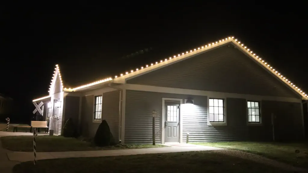A building at the Sioux City Railroad Museum with warm white bulbs along every gable and eave