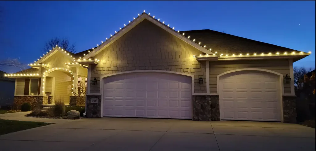 Warm white lights along every gable and eave of a Sioux City area home at blue hour