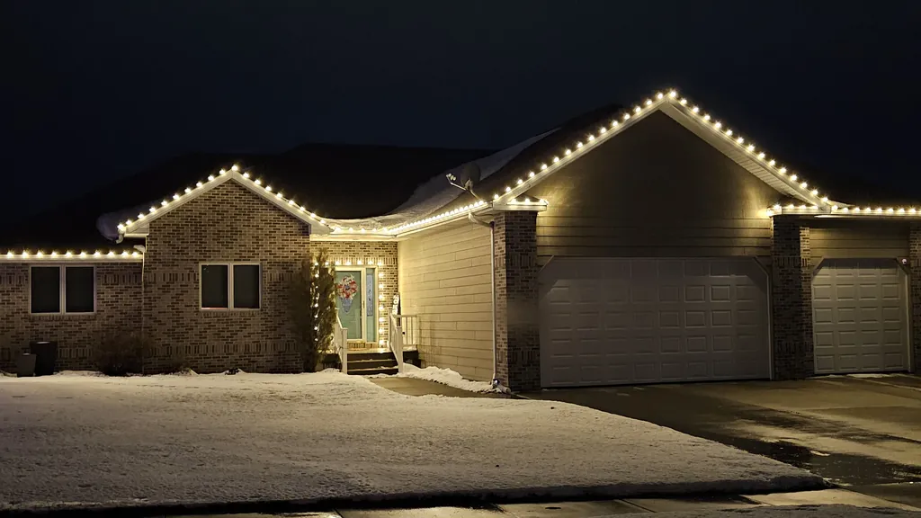 A brick and cream ranch in Sioux City on a snowy night with bulbs following every eave and gable