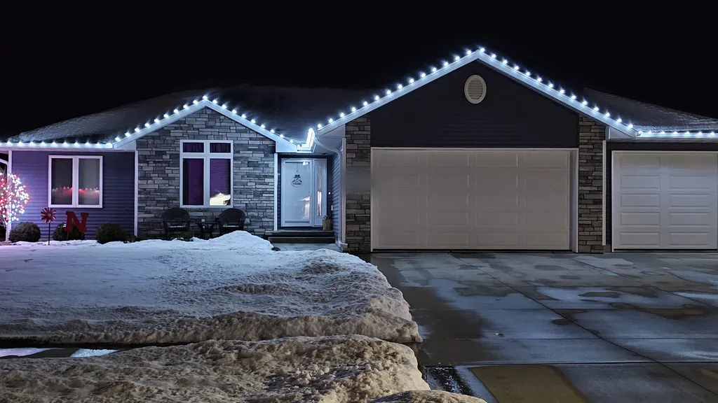 A Sioux City home lit in cool white, square on, with a swept driveway leading in