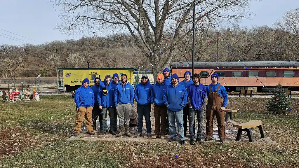 The Sharp Lawn Care crew in Sharp blue in front of the museum rolling stock