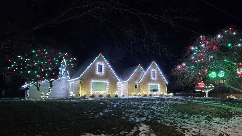 Steep gables picked out in cool white with red and green carried into the yard trees
