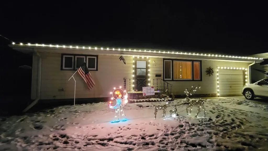 Warm white Christmas lights outlining the roof, garage and front door of a Siouxland home with snow on the ground