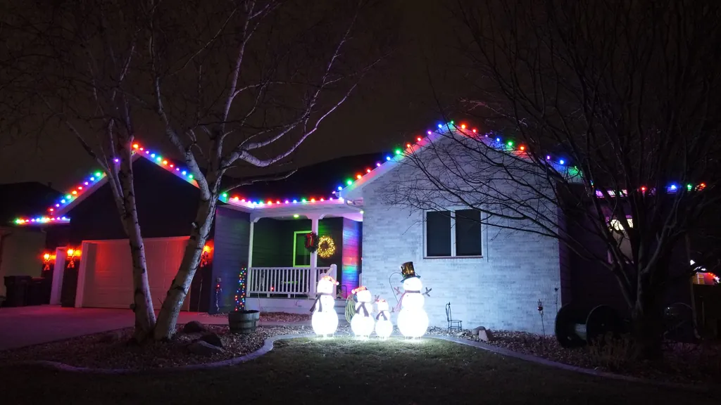 Sharp multicolor Christmas lights along the roof of a Sioux Falls home with lit figures in the yard