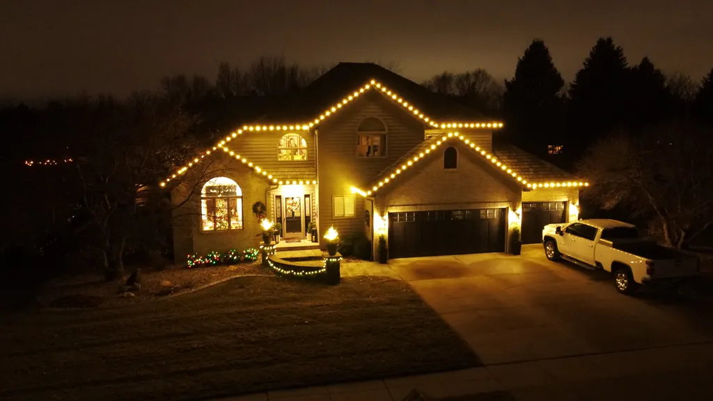 Warm white Christmas lights across a full roof line on a Sioux Falls home seen from above