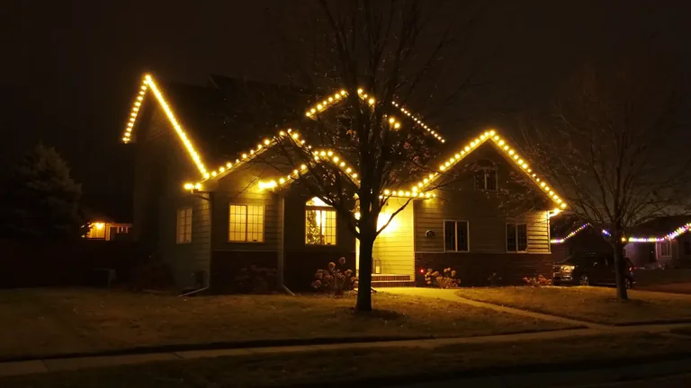 Warm golden Christmas lights tracing every gable of a Sioux Falls house at night