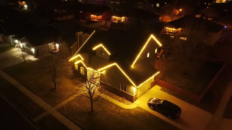 Warm white Christmas lights on the roofline, garage and entry of a Sioux Falls home at night