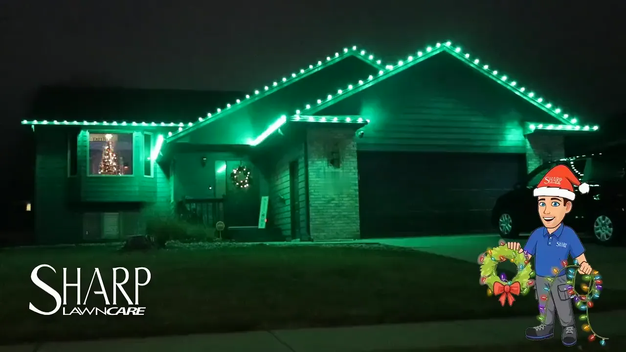 A Sioux Falls home at night with the roof line and both gables traced in green bulbs